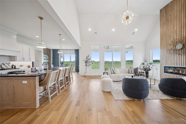 2509 E 134th Cir, Bixby, OK 74008 - living area with high vaulted ceiling, light wood finished floors, healthy amount of natural light, a glass covered fireplace, and recessed lighting