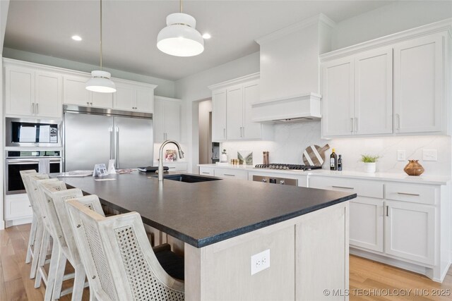 2509 E 134th Cir, Bixby, OK 74008 - kitchen with built in appliances, light wood-style flooring, a breakfast bar area, white cabinets, and recessed lighting