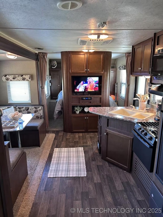 kitchen with dark hardwood / wood-style flooring, stainless steel gas range, a textured ceiling, dark brown cabinetry, and sink