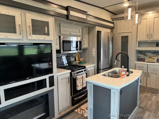 kitchen featuring pendant lighting, backsplash, sink, an island with sink, and stainless steel appliances