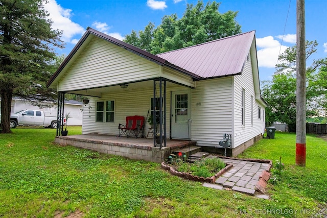 rear view of house featuring a lawn and a porch