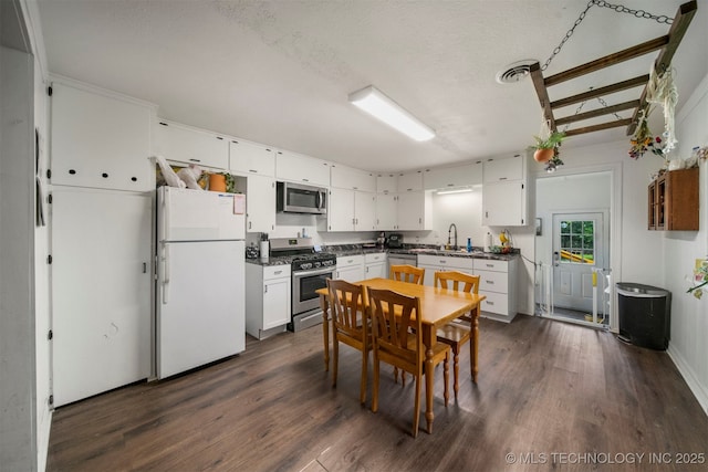 kitchen with white cabinets, dark hardwood / wood-style floors, stainless steel appliances, and a textured ceiling