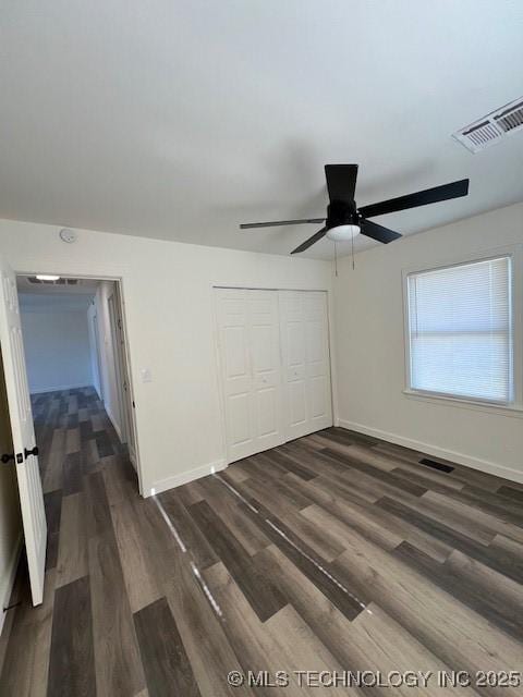 unfurnished bedroom featuring ceiling fan, dark hardwood / wood-style floors, and a closet