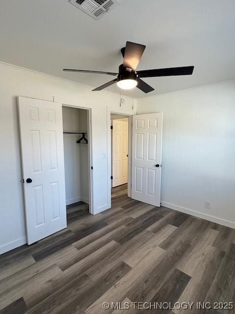 unfurnished bedroom with ceiling fan, ornamental molding, dark wood-type flooring, and a closet