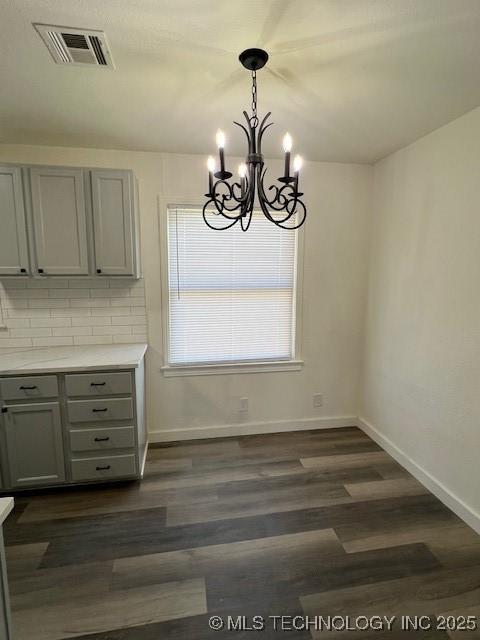 unfurnished dining area with dark hardwood / wood-style floors and a chandelier