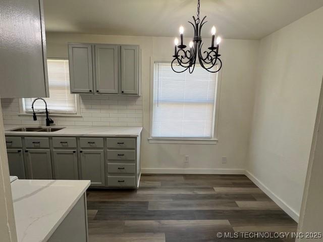 kitchen with dark hardwood / wood-style flooring, tasteful backsplash, sink, an inviting chandelier, and hanging light fixtures