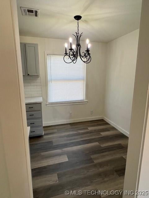 unfurnished dining area with dark hardwood / wood-style floors and an inviting chandelier