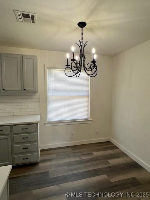 unfurnished dining area with a notable chandelier and dark hardwood / wood-style floors