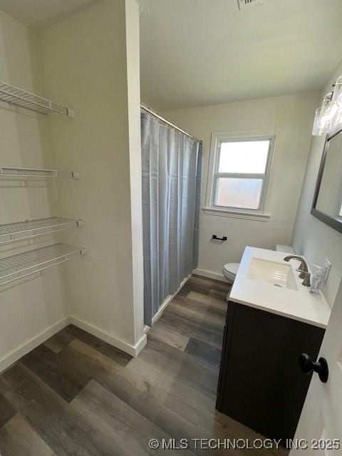 bathroom featuring wood-type flooring, vanity, toilet, and walk in shower