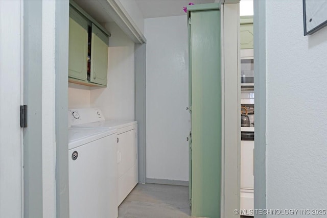 clothes washing area featuring washing machine and clothes dryer and cabinets