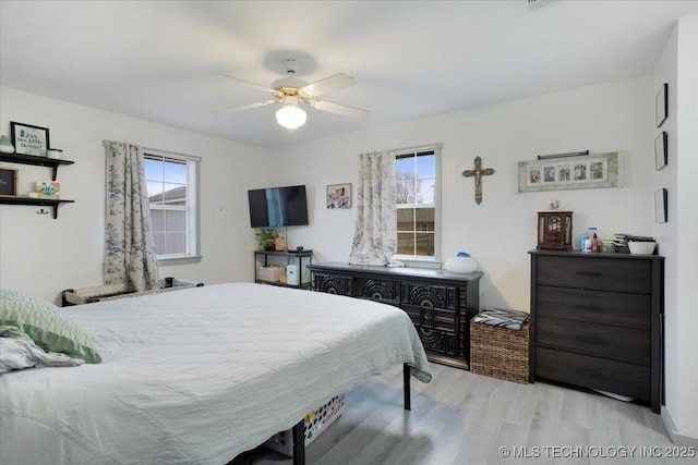 bedroom with ceiling fan, light hardwood / wood-style floors, and multiple windows