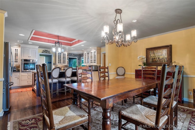 dining area with hardwood / wood-style floors, a tray ceiling, crown molding, and a notable chandelier