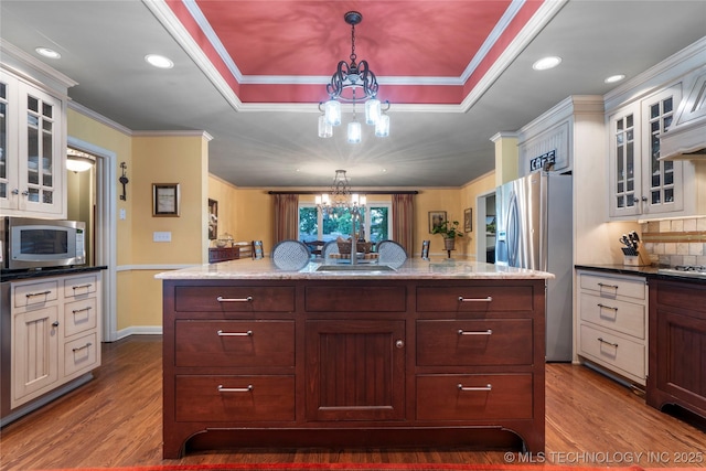 kitchen with appliances with stainless steel finishes, ornamental molding, sink, pendant lighting, and a chandelier