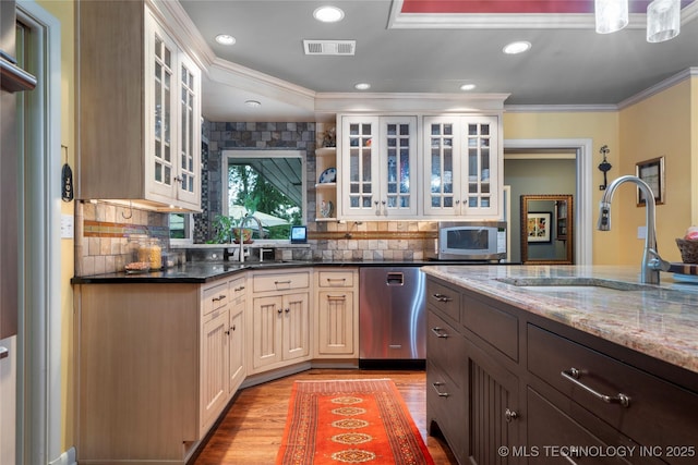 kitchen featuring dark stone counters, crown molding, sink, appliances with stainless steel finishes, and dark brown cabinetry