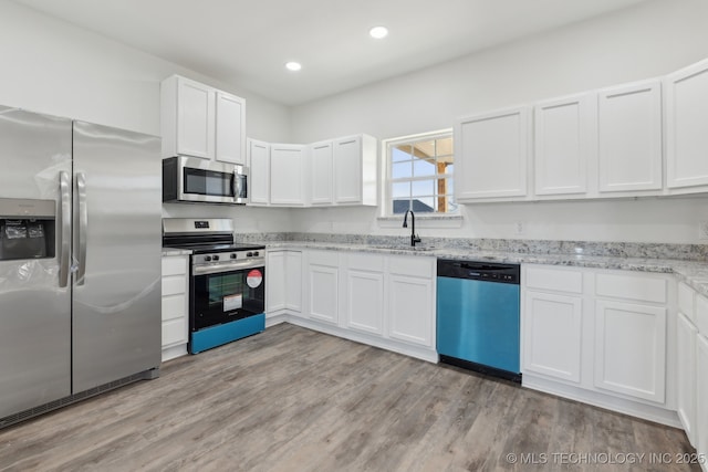 kitchen featuring white cabinetry, sink, light hardwood / wood-style flooring, and appliances with stainless steel finishes