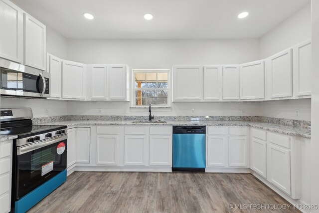 kitchen with light stone counters, sink, white cabinets, and appliances with stainless steel finishes