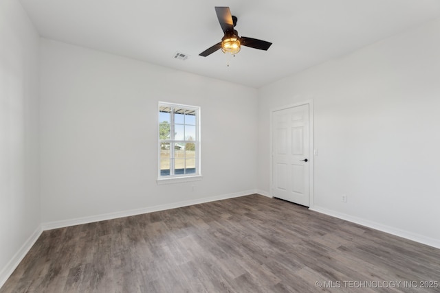 spare room with a ceiling fan, visible vents, wood finished floors, and baseboards