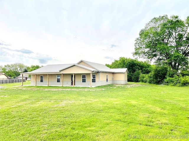 back of property with a lawn and fence
