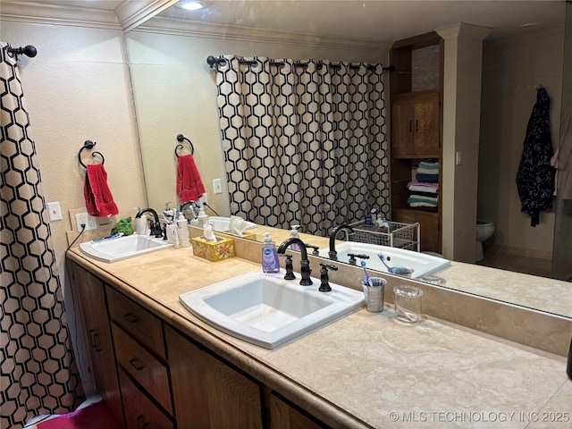 full bath featuring double vanity, a sink, toilet, and crown molding