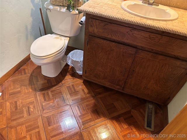 bathroom featuring visible vents, a textured wall, toilet, vanity, and baseboards