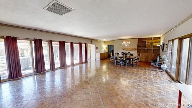 interior space with visible vents, a chandelier, and ornamental molding