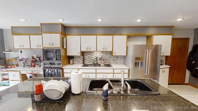 kitchen with tasteful backsplash, white cabinets, black appliances, a sink, and recessed lighting