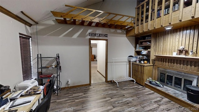 interior space with a high ceiling, baseboards, wood finished floors, and a glass covered fireplace