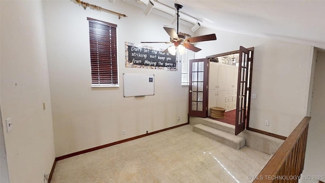 empty room with baseboards, vaulted ceiling, a ceiling fan, and light colored carpet