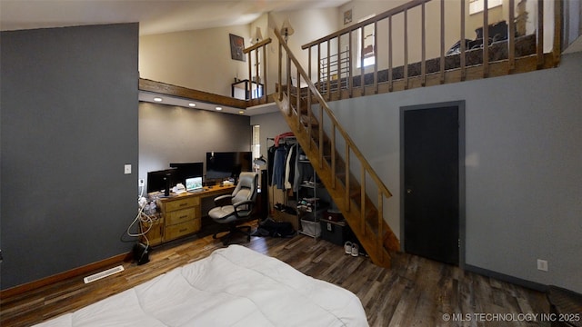 office with high vaulted ceiling, visible vents, baseboards, and wood finished floors