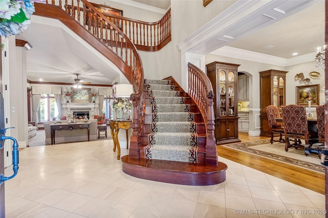 stairs featuring tile patterned flooring, ceiling fan, and ornamental molding