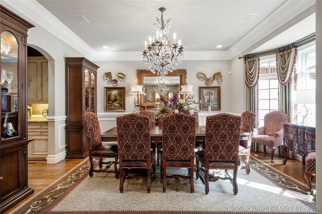 dining room with crown molding, a notable chandelier, and light wood-type flooring