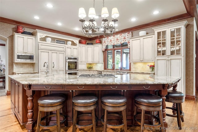 kitchen featuring built in appliances, hanging light fixtures, a spacious island, and light wood-type flooring