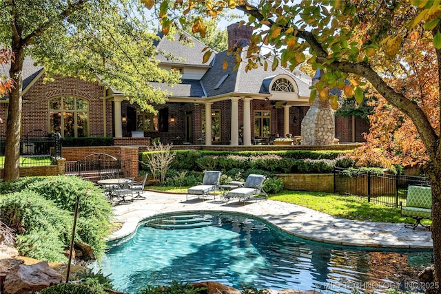 rear view of house featuring a fenced in pool and a patio