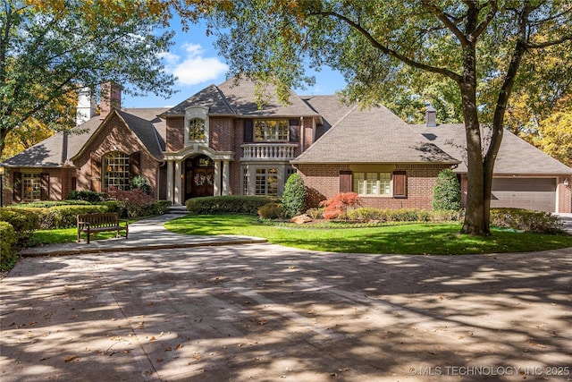 tudor house featuring a garage and a front lawn