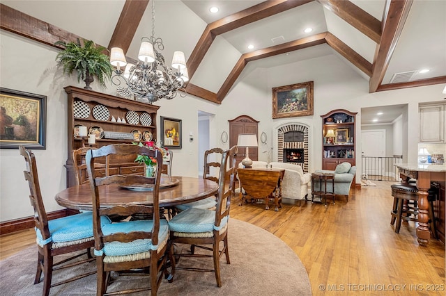 dining area featuring high vaulted ceiling, light hardwood / wood-style floors, and an inviting chandelier