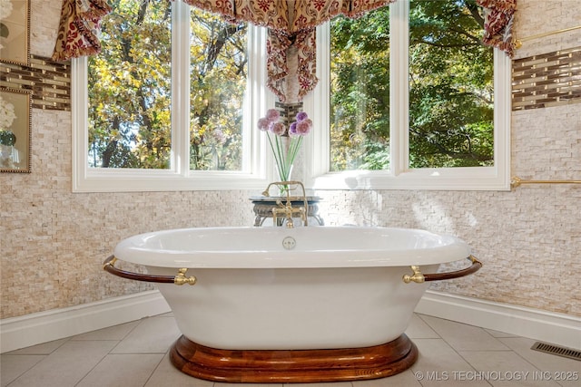 bathroom with tile patterned floors, a bathtub, and a wealth of natural light