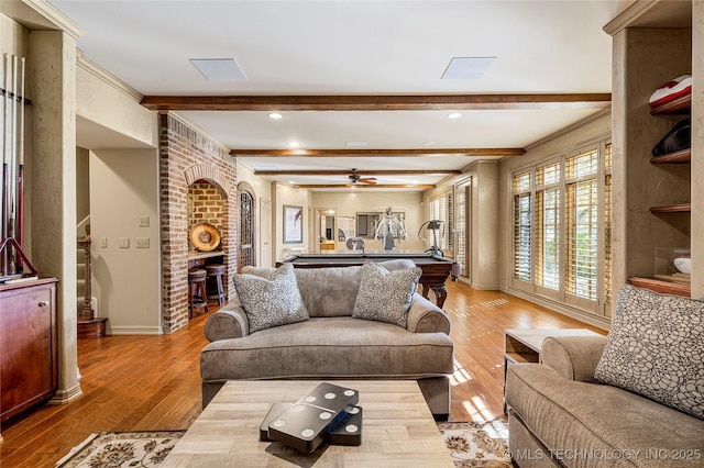 living room featuring hardwood / wood-style floors, ceiling fan, and beam ceiling