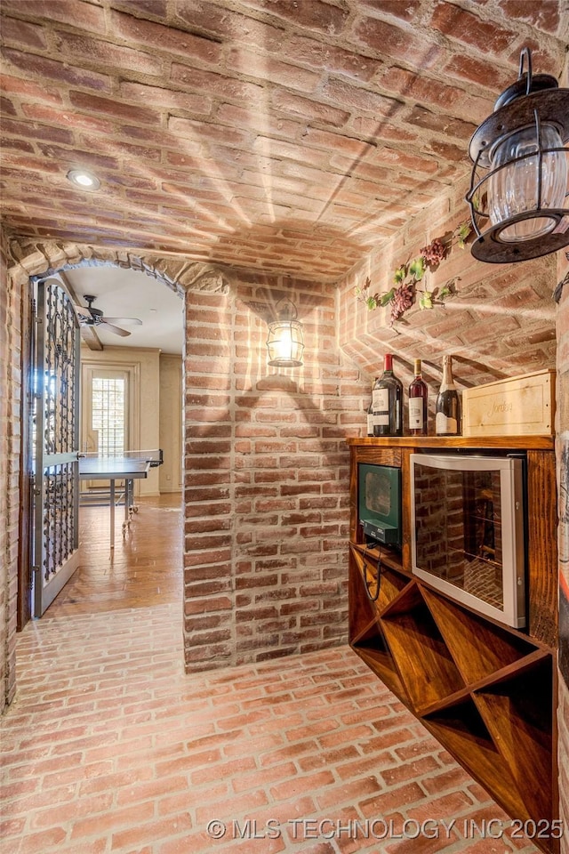 wine room with ceiling fan, brick ceiling, and wine cooler