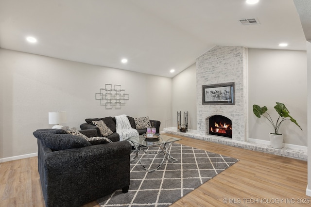 living room featuring hardwood / wood-style floors, a large fireplace, and vaulted ceiling