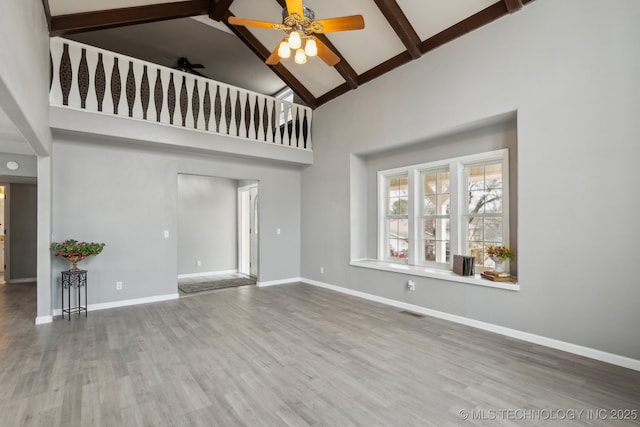 unfurnished living room with hardwood / wood-style flooring, ceiling fan, beam ceiling, and high vaulted ceiling