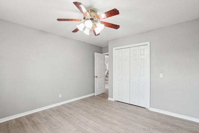 unfurnished bedroom featuring ceiling fan, a closet, and light hardwood / wood-style flooring