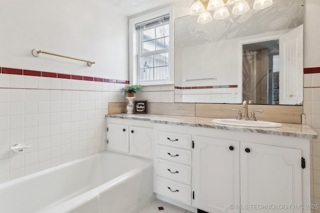 bathroom featuring vanity, tile walls, and a washtub