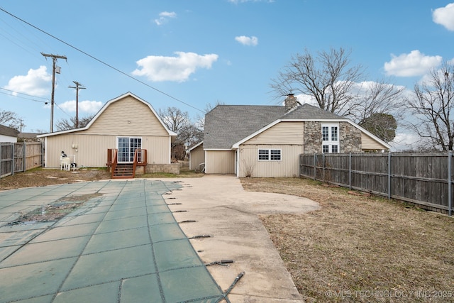 back of property featuring an outbuilding, a patio, and a covered pool