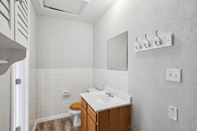 bathroom featuring vanity, toilet, hardwood / wood-style floors, and tile walls