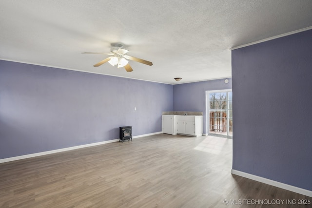 201 Sandy Cir, Tahlequah, OK 74464 - unfurnished living room with a wood stove, a ceiling fan, wood finished floors, a textured ceiling, and baseboards