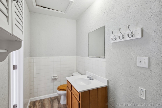 201 Sandy Cir, Tahlequah, OK 74464 - bathroom featuring toilet, vanity, tile walls, wood finished floors, and a wainscoted wall