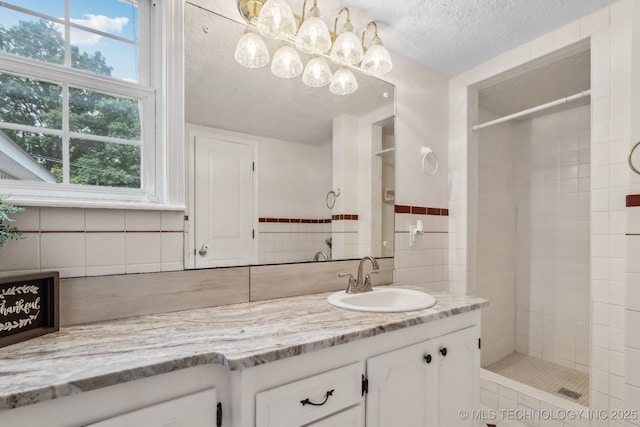 201 Sandy Cir, Tahlequah, OK 74464 - bathroom with vanity, tiled shower, a textured ceiling, a chandelier, and tile walls
