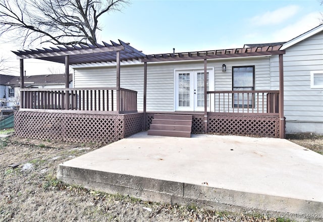 rear view of property with a pergola, a wooden deck, and a patio