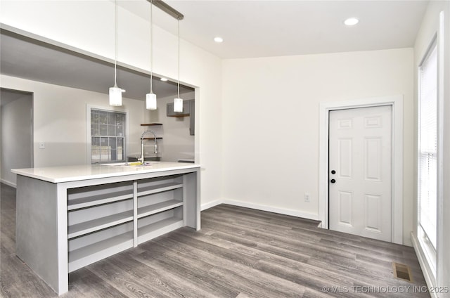 kitchen with pendant lighting, kitchen peninsula, sink, and dark wood-type flooring