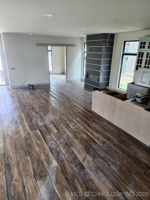 unfurnished living room with a large fireplace and dark wood-type flooring